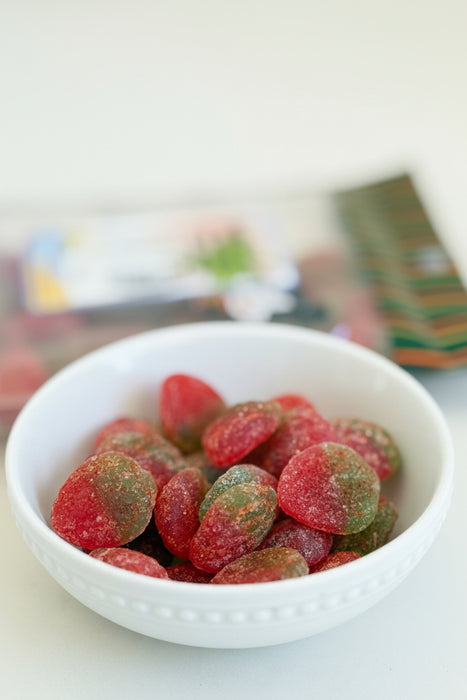 White bowl filled with red and green gummy candies on a blurred background