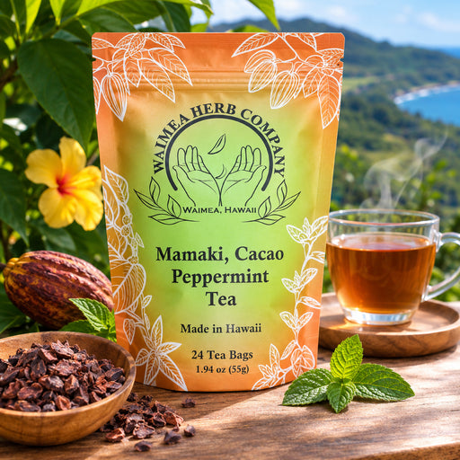 Orange and green bag of mamaki, cacao peppermint tea. Cacao pod in back left. Wooden bowl of crushed cacao in front. Glass mug of tea on right with mint in front. 