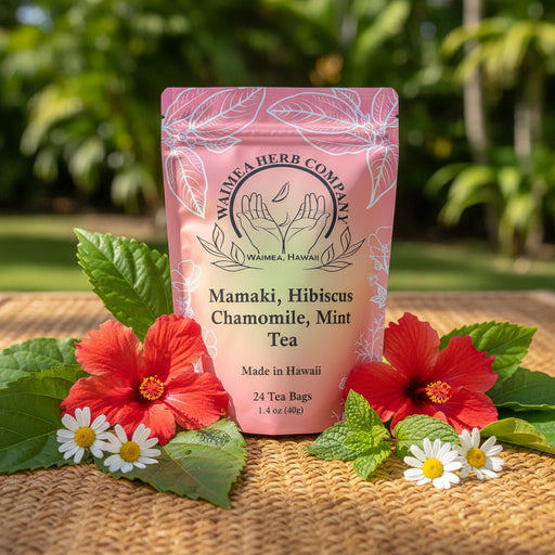 Pink mamaki tea bag with red hibiscus, mint and chamomile flowers in front.