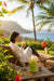 woman drinking tea with a Hawaiian landscape in the background.
