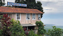 Wooden building with 'The Coffee Shack' sign, surrounded by greenery and overlooking a scenic landscape.