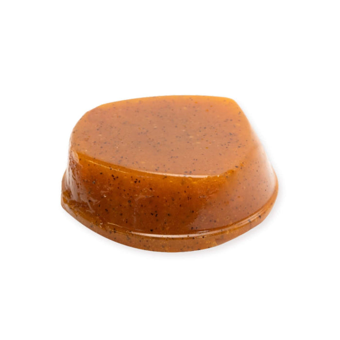 A single dome-shaped POG fruit paste with a glossy amber-brown surface and small dark specks, isolated on a plain white background.